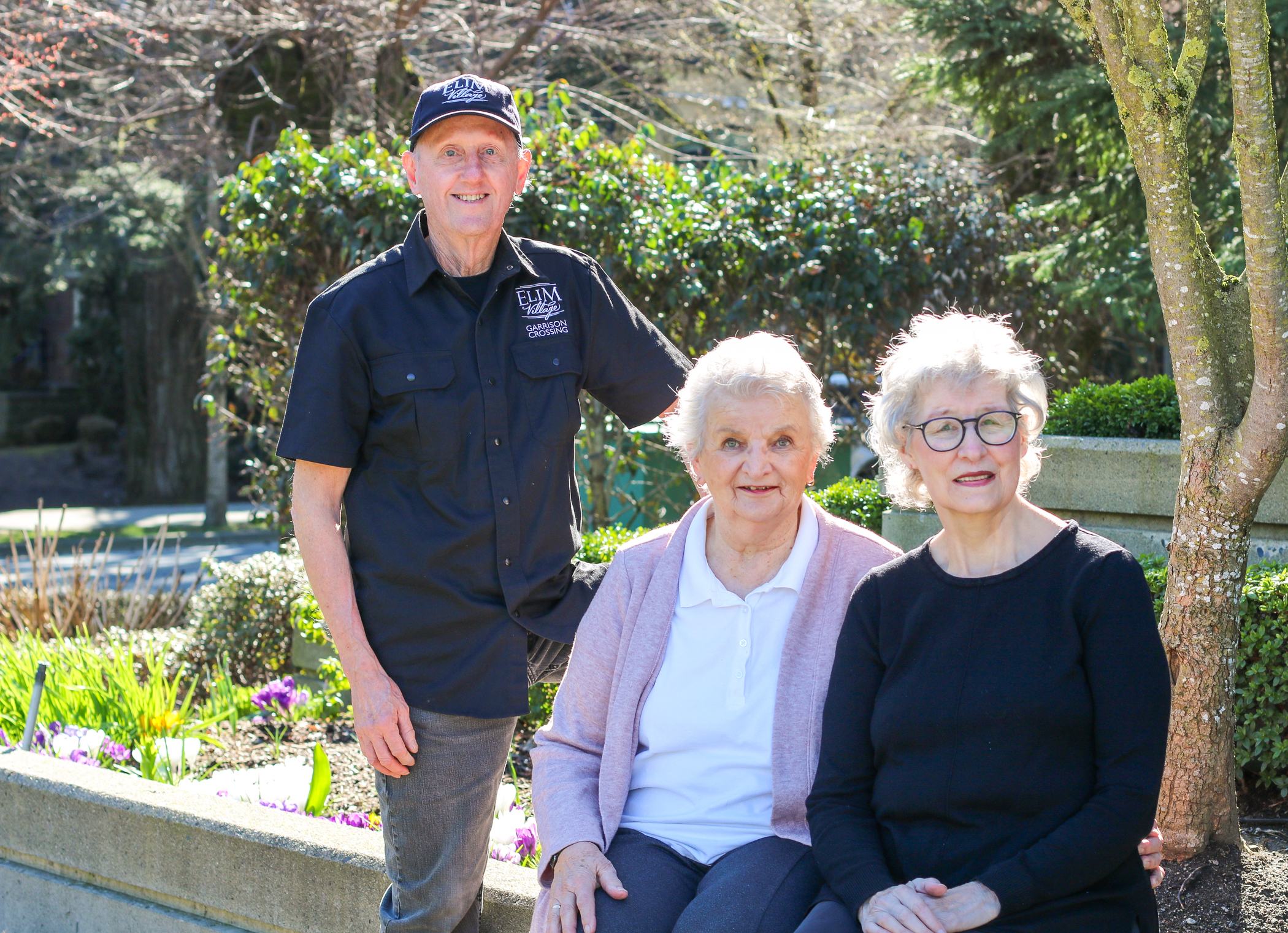 Don, Anne, and Millie enjoy the sunshine and beautiful flowers onsite at Elim Village Garrison Crossing